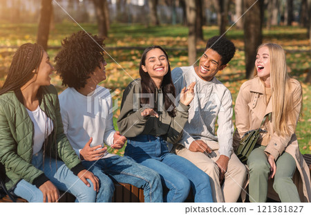 Group of international teenagers having fun in public park, talking and laughing 121381827