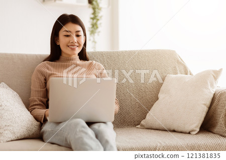 Modern Job Lifestyle. Young Girl Sitting on Sofa at Home Working on Laptop Online, Using Internet, Free Space 121381835