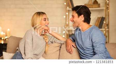 Enjoy weekends. Happy couple talking and eating popcorn in cozy living room, free space 121381853