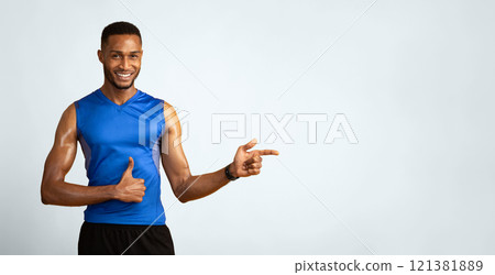 Cool Offer. Smiling black sportive guy pointing index finger aside at copyspace, showing thumb up on yellow studio wall Cool Offer. Smiling black sportive guy pointing index finger aside at copyspace, showing thumb up on yellow studio wall 121381889
