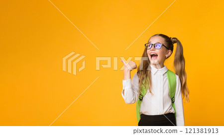Look There. Excited Elementary Student Girl Pointing Thumb At Free Space Over Yellow Background In Studio. Panorama 121381913