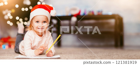 Funny toddler girl drawing wish list for Santa Claus, lying on floor at home, free space Funny toddler girl drawing wish list for Santa Claus, lying on floor at home, free space 121381919