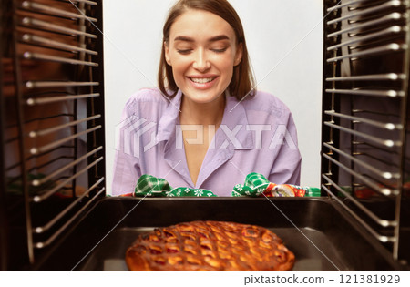 Cheerful millennial housewife taking tasty sweet pie from oven, view from inside 121381929