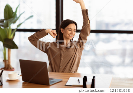 Stress Relief. Smiling young businesswoman is relaxing in her office and stretching her body, copyspace Stress Relief. Smiling young businesswoman is relaxing in her office and stretching her body, copyspace 121381938