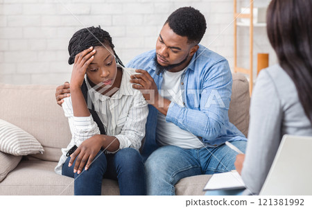 Loving husband supporting his depressed wife during psychotherapy session with counselor, free space 121381992