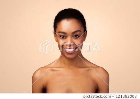 Female Beauty Portrait. Attractive African American Woman Smiling Looking At Camera Posing Shirtless Expressing Positive Emotions Over Gray Studio Background. Sensuality And Body Care Concept Female Beauty Portrait. Attractive African American Woman Smiling Looking At Camera Posing Shirtless Expressing Positive Emotions Over Gray Studio Background. Sensuality And Body Care Concept 121382008