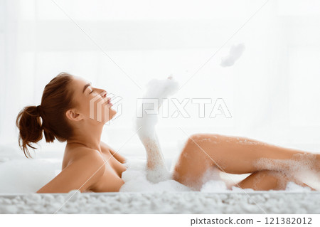 Relaxing In Bathtub. Young Woman Having Fun With Foam In Bathroom 121382012