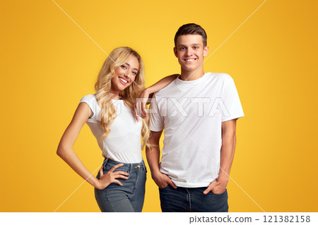 Cool millennials. Smiling guy and girl posing over yellow background, copy space 121382158
