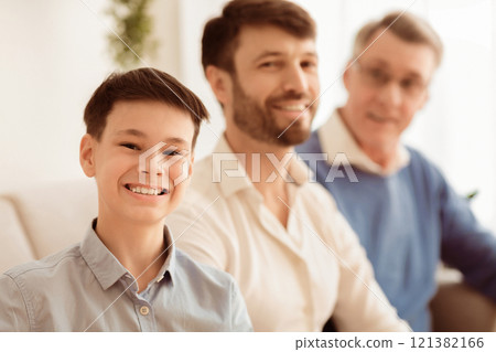 Male Family. Cheerful Boy With Father And Grandfather Smiling At Camera Sitting On Couch At Home. Shallow Depth Male Family. Cheerful Boy With Father And Grandfather Smiling At Camera Sitting On Couch At Home. Shallow Depth 121382166