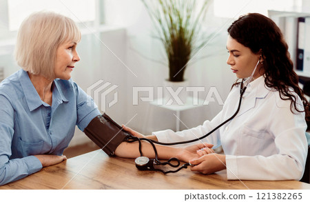 Cardiology. Mexican doctor measuring blood pressure of senior woman, checking patient, free space, panorama Cardiology. Mexican doctor measuring blood pressure of senior woman, checking patient, free space, panorama 121382265
