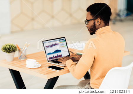 Computer Screen With Graphics And Chart. Rear view of african american businessman working on laptop with graphs 121382324