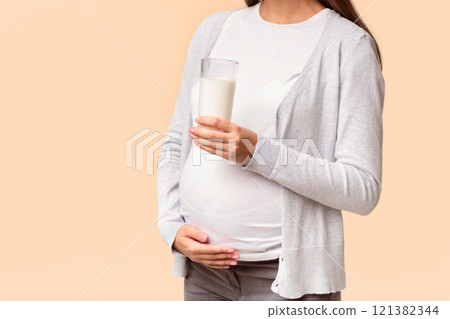 Unrecognizable Pregnant Young Woman Holding Glass Of Milk Standing On White Studio Background. Dairy And Calcium In Pregnancy. Cropped 121382344