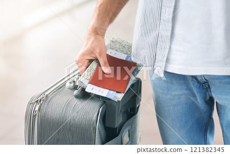 Travelling concept. Man holding his passport and carrying suitcase, close up 121382345