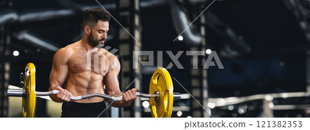 A muscular man performs a bicep curl with a barbell in a well-equipped gym, focusing on his workout, copy space A muscular man performs a bicep curl with a barbell in a well-equipped gym, focusing on his workout, copy space 121382353
