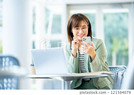 A woman operating a smartphone A female employee using a smartphone A woman operating a smartphone A female employee using a smartphone 121384079