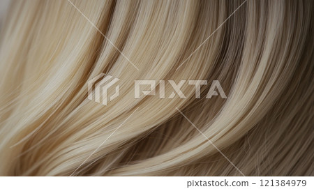 Soft, silky strands of blonde hair cascade in gentle waves, catching the light beautifully, creating a lush texture. 121384979