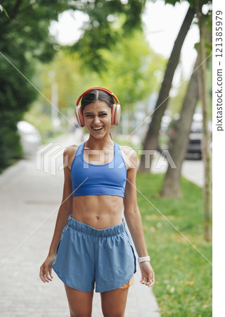 An energetic young woman is seen jogging through a vibrant city park enjoying the outdoors 121385979