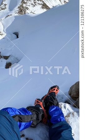 Legs of a tourist on the top of a snowy mountain. Vertical photo. 121386275