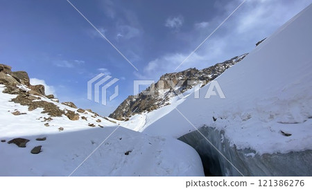 Rocky peak of snow-capped mountain against blue sky Rocky peak of snow-capped mountain against blue sky 121386276