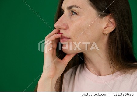 Beautiful thoughtful woman looking up, different emotions of a young girl on a green background chromakey beautiful facial features real people pink T-shirt white skinned. European Beautiful thoughtful woman looking up, different emotions of a young girl on a green background chromakey beautiful facial features real people pink T-shirt white skinned. European 121386656