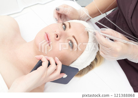 Female adult caucasian receiving facial beauty treatment while talking on phone Female adult caucasian receiving facial beauty treatment while talking on phone 121388868