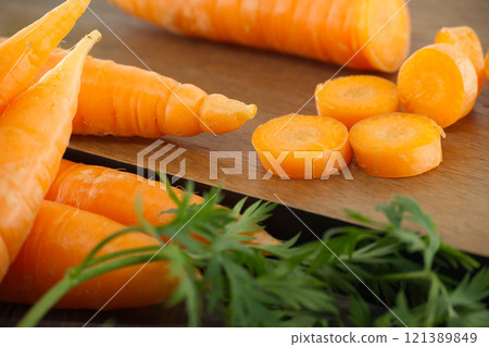 Fresh Carrots on Wooden Surface With Sliced Pieces Displayed 121389849