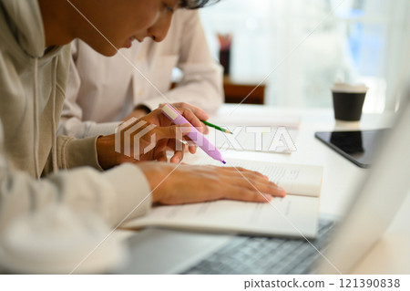 Close up shot of student highlighting important text with a marker while studying with his tutor Close up shot of student highlighting important text with a marker while studying with his tutor 121390838