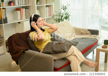 Happy young woman relaxing while listening to music with wireless headphones 121390842