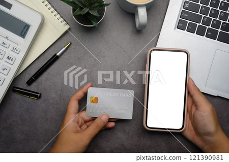 Hand holding smartphone with blank screen a credit card. Online shopping, financial transactions and e-commerce Hand holding smartphone with blank screen a credit card. Online shopping, financial transactions and e-commerce 121390981