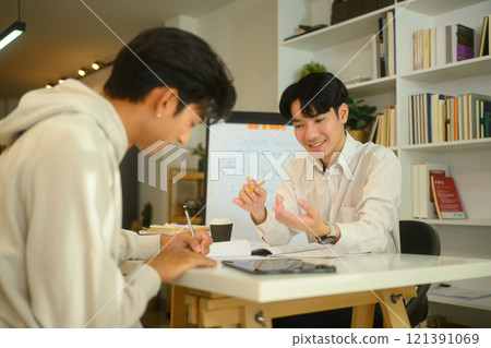 Tutor and student sharing ideas and discussing study materials during a home tutoring session 121391069
