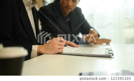 Business advisor pointing to a document discussing key details with a client before signing Business advisor pointing to a document discussing key details with a client before signing 121391103