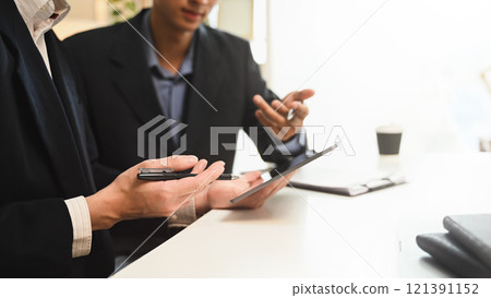 Professional financial advisor in formal suit explaining details on digital tablet to a client 121391152