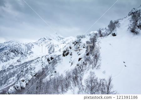High mountain peaks covered with snow on a winter cloudy day High mountain peaks covered with snow on a winter cloudy day 121391186