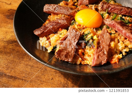 Bibimbap-style fried rice topped with grilled beef skirt steak and egg yolk 121391853