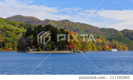 秋天的信州信濃町，白色的遊船在藍色野尻湖的弁天島（宇賀神社）周圍巡遊。 121392065