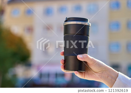 Woman holding reusable coffee cup outdoors in autumn 121392619