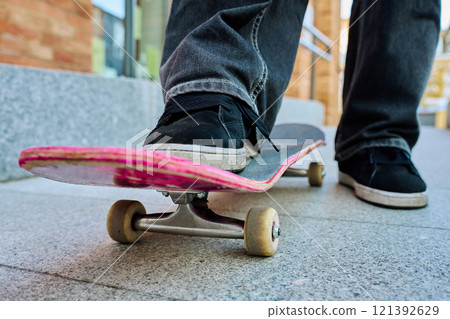 Skateboarder riding on pink skateboard at city street Skateboarder riding on pink skateboard at city street 121392629
