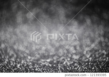 A bokeh background in black and white tones with small particles shining through. 121393395