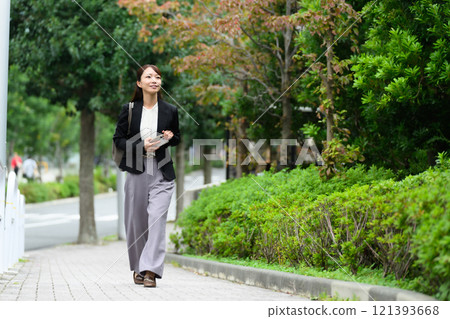 Middle-aged woman walking on the sidewalk Business 121393668