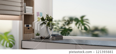 A close-up of a modern desk featuring books and vases in a modern room with a large window. 121393881