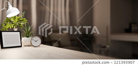 A wooden table featuring decor in a cozy living room at night, softly illuminated by a table lamp. 121393907