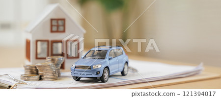 Financial planning concept with a car and house model, coins, and documents. Represents banking, savings, and real estate strategies for managing investments 121394017