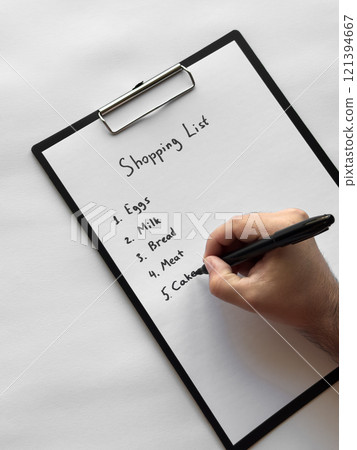 Hand writing shopping list on clipboard with eggs, milk, bread, meat, cakes items Hand writing shopping list on clipboard with eggs, milk, bread, meat, cakes items 121394667