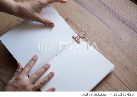 Hand Clipping a Binder to Paperwork on a Desk 121395420