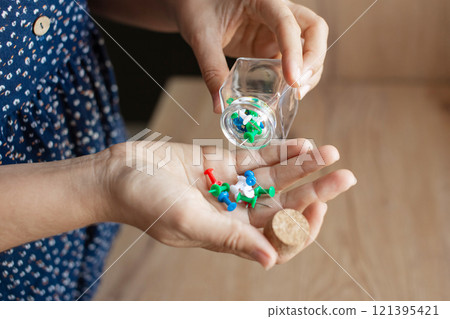 Hands Holding Glass Jar with Paper Clips 121395421