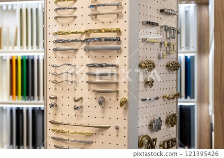 Display of assorted cabinet handles and knobs on pegboard. Interior design and hardware selection. Display of assorted cabinet handles and knobs on pegboard. Interior design and hardware selection. 121395426