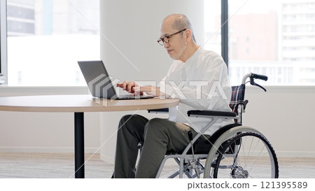 Elderly person in a wheelchair operating a computer 121395589