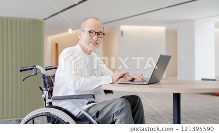 Elderly person in a wheelchair operating a computer 121395590
