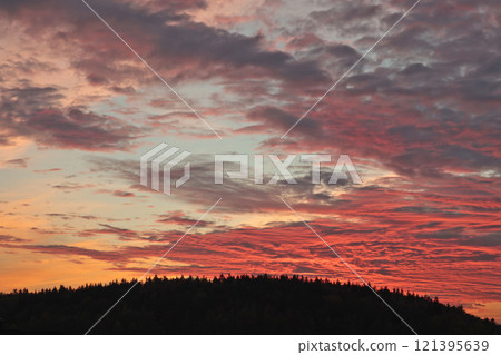 Orange, red sunset over forest and village. Romantic dramatic background for design. Sky and clouds. Orange, red sunset over forest and village. Romantic dramatic background for design. Sky and clouds. 121395639