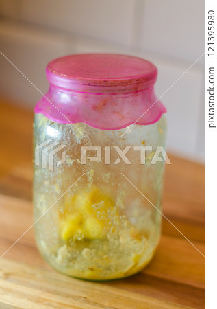 Dirty glass Jar with Pink Lid and Leftovers on wooden table in kitchen . High quality photo 121395980